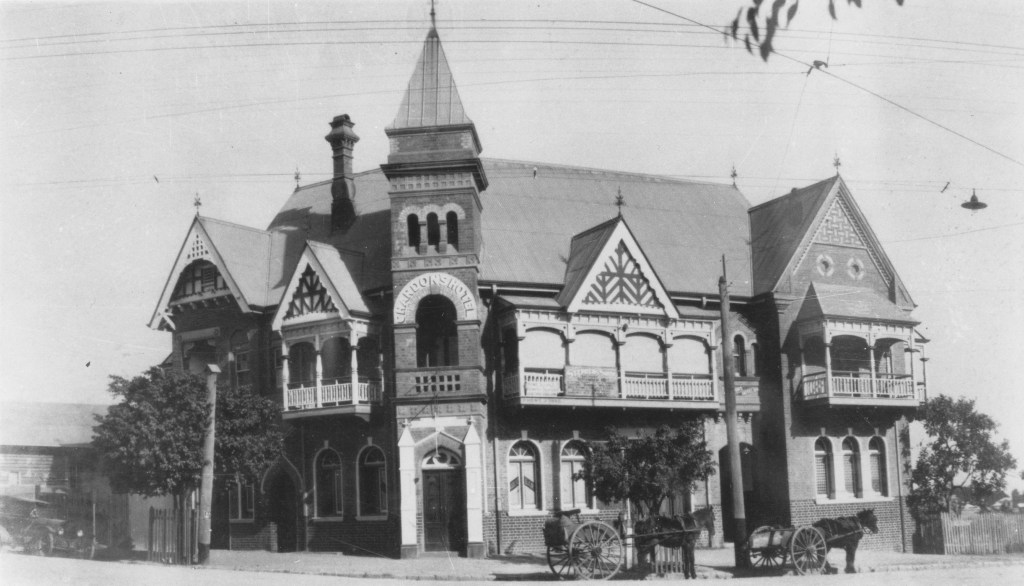 Black and white photograph of the Chardon’s Hotel, a 2-story brick building with gabling and verandahs on the second floor. Designed by prominent Brisbane architect John Beauchamp Nicholson, the hotel was erected in ca. 1892 upon the southeast corner of Ipswich Road and Cracknell Road, Annerley, known today as Chardon's Corner. The first licensee was T. F. Chardon.