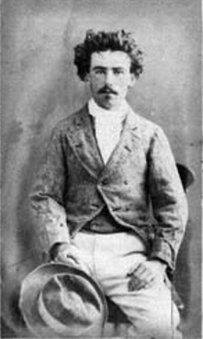 This image is of Timothy Duffy's son, James, on admission to Brisbane Gaol in 1875. It depicts a man in his late teens, with thick, dark, curly hair and a moustache. He is sitting in a wooden chair, wearing a pair of pale trousers, what appears to be a cravat or neck scarf, a tweed-style wide-lapelled jacket with one button done up. One hand is visible and rests on his leg. The other hand is obscured by his hat. James Duffy had an injury that damaged one of his hands, and he is hiding the injured hand in this photo. The photo is put in to show what Timothy Duffy, his father, might have looked like in his youth. Their descriptions are similar.