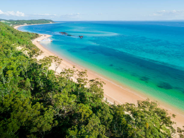 This image is an aerial photograph in colour, showing Moreton Island from above. It depicts the bushland, a wide, sandy beach, and Moreton Bay itself, and is intended to show how beautiful the Bay must have been as a workplace.