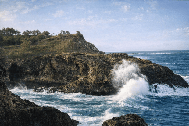 Colourised image of waves breaking on rocks on Stradbroke Island around 1920. Used to illustrate the heavy seas of Moreton Bay.